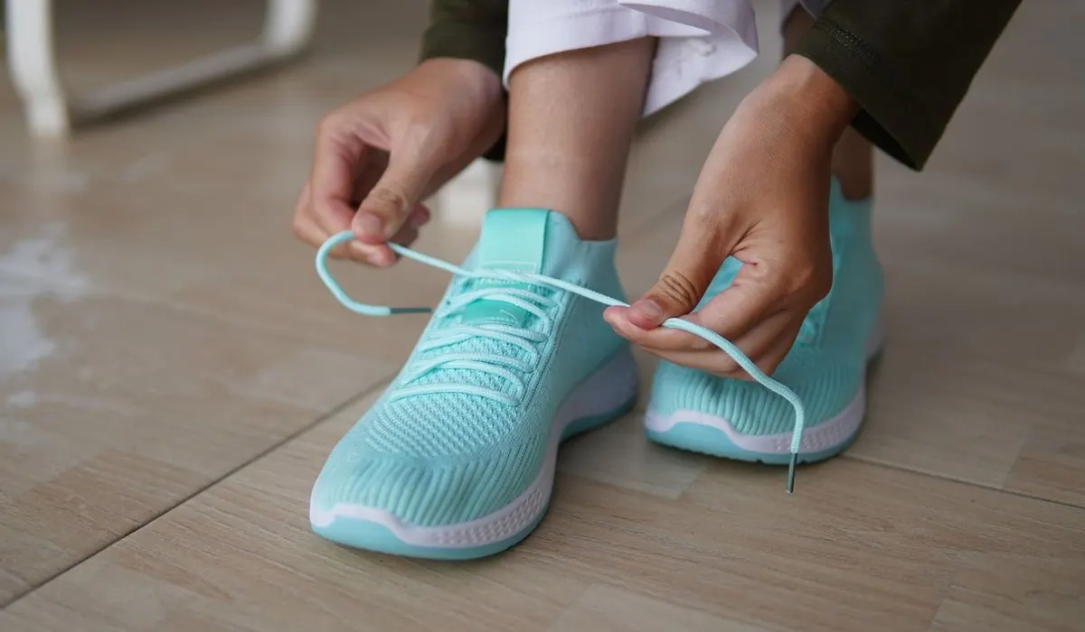 Mains qui lacent une paire de baskets en maille