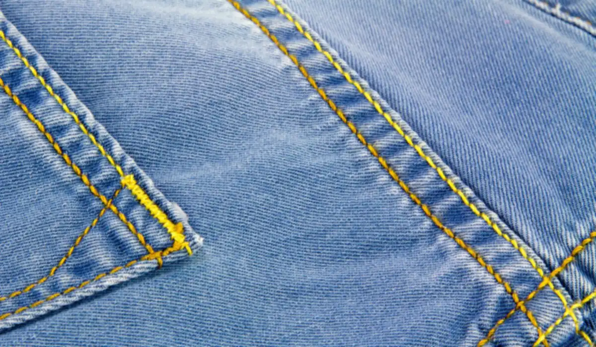 Surpiqûres jaunes sur la poche arrière d'un jean bleu