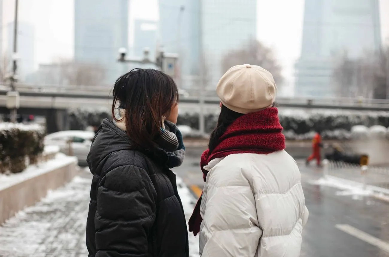 Two women in winter coats in a snowy city
