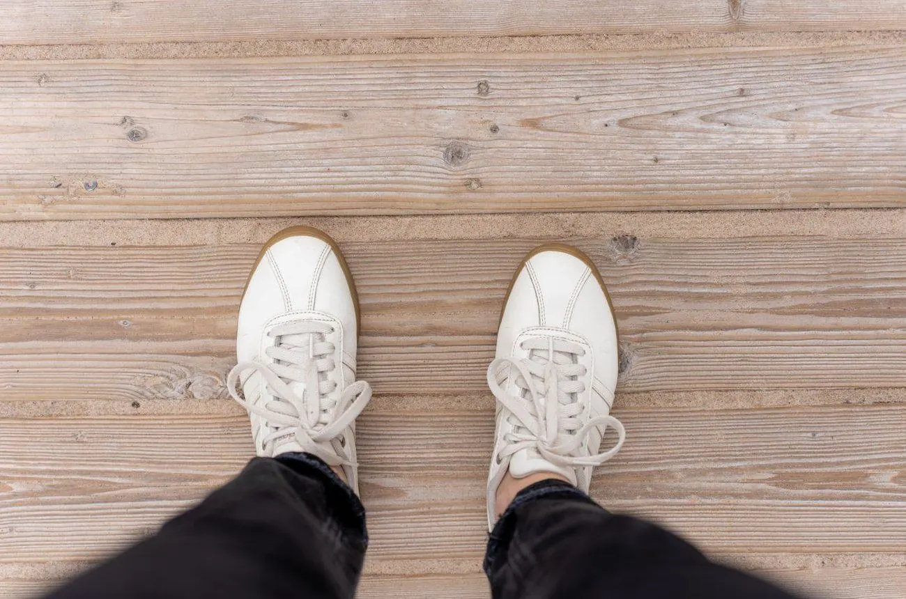 Pair of white leather trainers on a wooden floor